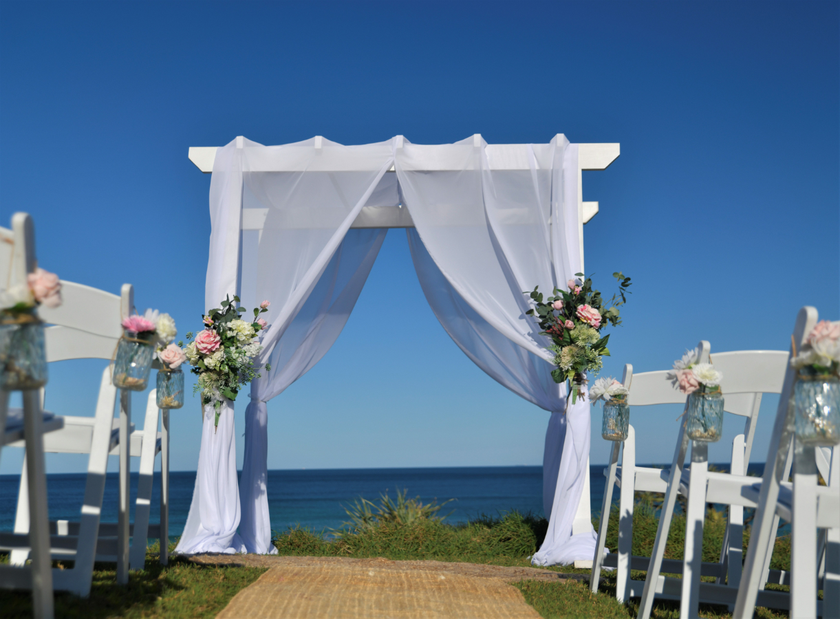 easy elopements and small weddings 4 post white wooden arbor with cloth draped and faux flowers.